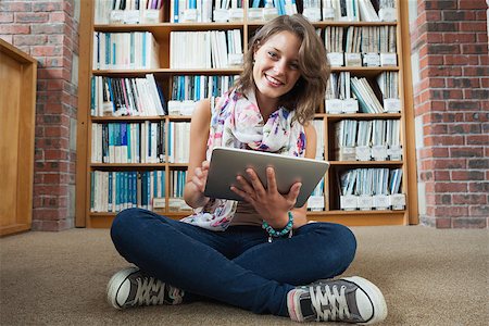 Full length portrait of a happy female student against bookshelf with tablet PC on the library floor Stock Photo - Budget Royalty-Free & Subscription, Code: 400-07142727