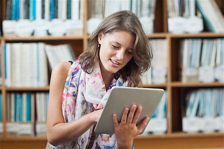 simsearch:400-07141917,k - Female student using tablet PC against bookshelf in the library Stock Photo - Budget Royalty-Free & Subscription, Code: 400-07142732