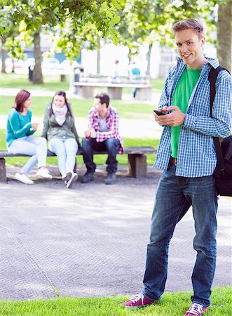 Portrait of a smiling college boy text messaging with blurred students sitting in the park Stock Photo - Budget Royalty-Free & Subscription, Code: 400-07143538