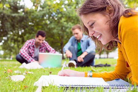 simsearch:632-05816947,k - Young student writing notes with two males using laptop in background at the park Foto de stock - Super Valor sin royalties y Suscripción, Código: 400-07143570