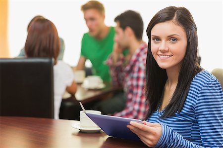 Portrait of a smiling female with coffee using tablet PC and students around table in background at  the coffee shop Stock Photo - Budget Royalty-Free & Subscription, Code: 400-07143625