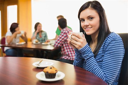 Smiling female having coffee and muffin with students around table in background at  the coffee shop Stock Photo - Budget Royalty-Free & Subscription, Code: 400-07143631