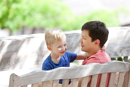 smiling positive father and his smiling adorable son sitting together and spending fun time outdoors Stock Photo - Budget Royalty-Free & Subscription, Code: 400-07165168