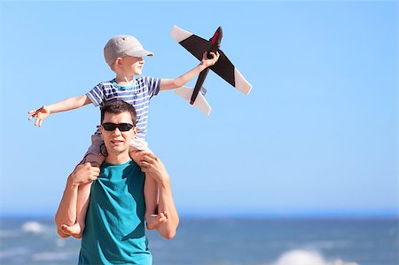 simsearch:400-04493361,k - smiling positive young man and his excited son sitting on father's shoulders and playing a toy plane at the beach Photographie de stock - Aubaine LD & Abonnement, Code: 400-07165163