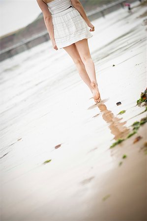 simsearch:400-04912125,k - Woman walking alone along the beach as the tide comes in Stock Photo - Budget Royalty-Free & Subscription, Code: 400-07165945