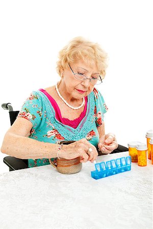pillbox - Senior woman in wheelchair sorting her medication for the week.  White background. Stock Photo - Budget Royalty-Free & Subscription, Code: 400-07168209