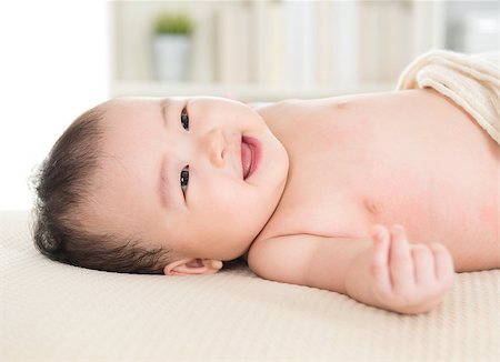 simsearch:400-07173561,k - Adorable six months old Asian baby girl lying on bed smiling. Foto de stock - Royalty-Free Super Valor e Assinatura, Número: 400-07168935