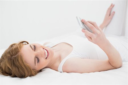 simsearch:693-06120706,k - Relaxed young woman looking at mobile phone in bed at home Stock Photo - Budget Royalty-Free & Subscription, Code: 400-07177019