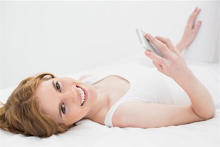 simsearch:693-06120706,k - Portrait of a relaxed young woman with mobile phone in bed at home Stock Photo - Budget Royalty-Free & Subscription, Code: 400-07177020