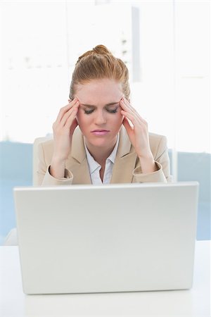 Young businesswoman suffering from headache in front of laptop at office desk Stock Photo - Budget Royalty-Free & Subscription, Code: 400-07177272