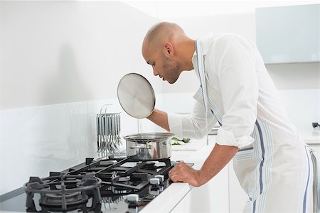 simsearch:400-07177497,k - Side view of a young man preparing food in the kitchen at home Foto de stock - Super Valor sin royalties y Suscripción, Código: 400-07177486