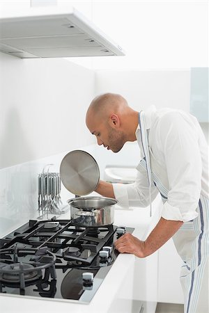 simsearch:400-07177497,k - Side view of a young man preparing food in the kitchen at home Foto de stock - Super Valor sin royalties y Suscripción, Código: 400-07177488