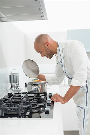 simsearch:400-07177497,k - Side view of a young man preparing food in the kitchen at home Foto de stock - Super Valor sin royalties y Suscripción, Código: 400-07177489