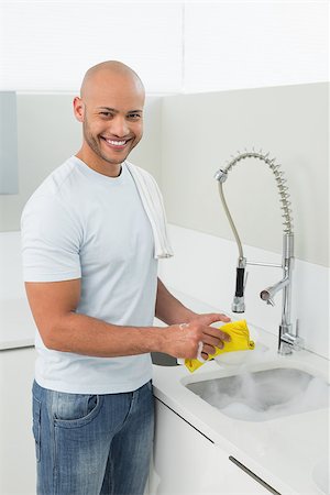 simsearch:400-07228658,k - Portrait of a smiling young man doing the dishes at kitchen sink in the house Stockbilder - Microstock & Abonnement, Bildnummer: 400-07177524