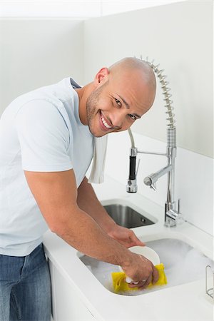 simsearch:400-07228658,k - Portrait of a smiling young man doing the dishes at kitchen sink in the house Stockbilder - Microstock & Abonnement, Bildnummer: 400-07177526