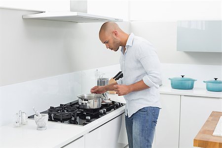 simsearch:400-07177497,k - Side view of a young man preparing food in the kitchen at home Foto de stock - Super Valor sin royalties y Suscripción, Código: 400-07177534