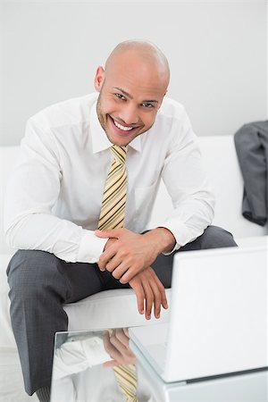 sophisticated home smile - Portrait of a smiling elegant young businessman using laptop on sofa at home Stock Photo - Budget Royalty-Free & Subscription, Code: 400-07177572