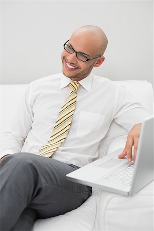 sophisticated home smile - Smiling elegant young businessman using laptop on sofa at home Stock Photo - Budget Royalty-Free & Subscription, Code: 400-07177584