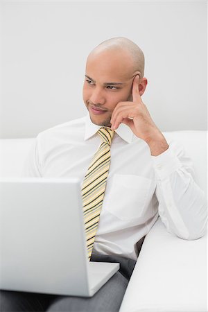 sophisticated home smile - Smiling elegant young businessman with laptop sitting on sofa at home Stock Photo - Budget Royalty-Free & Subscription, Code: 400-07177587