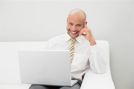 sophisticated home smile - Portrait of a smiling elegant young businessman with laptop sitting on sofa at home Stock Photo - Budget Royalty-Free & Subscription, Code: 400-07177589