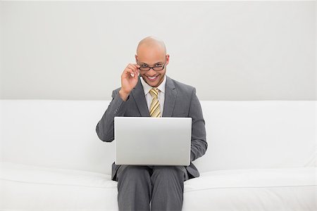 sophisticated home smile - Smiling elegant young businessman using laptop on sofa at home Stock Photo - Budget Royalty-Free & Subscription, Code: 400-07177594