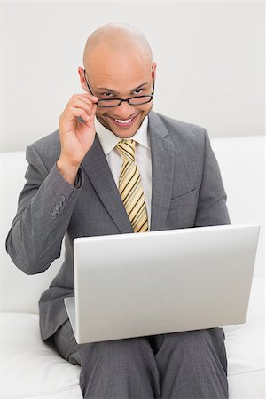 sophisticated home smile - Smiling elegant young businessman using laptop on sofa at home Stock Photo - Budget Royalty-Free & Subscription, Code: 400-07177597