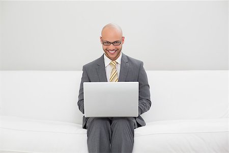 sophisticated home smile - Smiling elegant young businessman using laptop on sofa at home Stock Photo - Budget Royalty-Free & Subscription, Code: 400-07177593