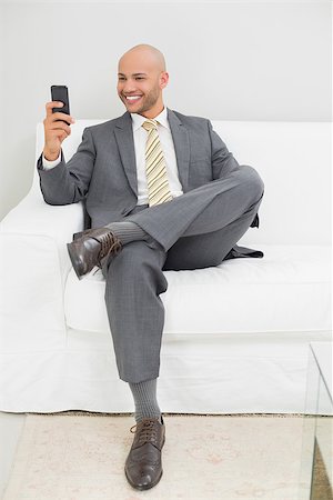 sophisticated home smile - Smiling elegant young businessman text messaging on sofa at home Stock Photo - Budget Royalty-Free & Subscription, Code: 400-07177606