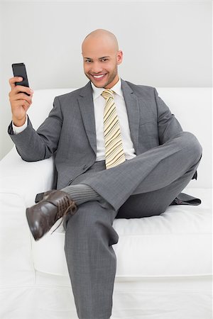 sophisticated home smile - Smiling elegant young businessman text messaging on sofa at home Stock Photo - Budget Royalty-Free & Subscription, Code: 400-07177607