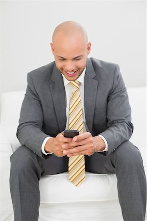 sophisticated home smile - Smiling elegant young businessman text messaging on sofa at home Stock Photo - Budget Royalty-Free & Subscription, Code: 400-07177615