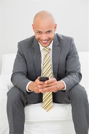 sophisticated home smile - Portrait of a smiling elegant young businessman text messaging on sofa at home Stock Photo - Budget Royalty-Free & Subscription, Code: 400-07177616