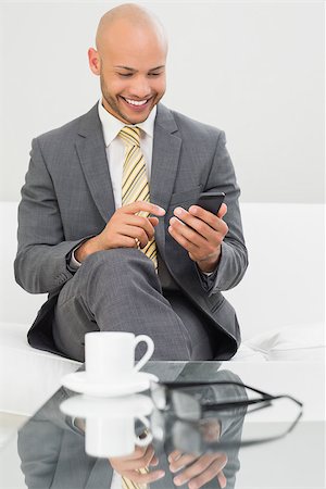 sophisticated home smile - Smiling elegant young businessman text messaging on sofa at home Stock Photo - Budget Royalty-Free & Subscription, Code: 400-07177627