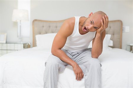 simsearch:614-06813544,k - Young bald man sitting and yawning in bed at home Stockbilder - Microstock & Abonnement, Bildnummer: 400-07177688