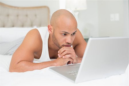 simsearch:400-07177497,k - Close up of a serious casual bald young man using laptop in bed at home Foto de stock - Super Valor sin royalties y Suscripción, Código: 400-07177716