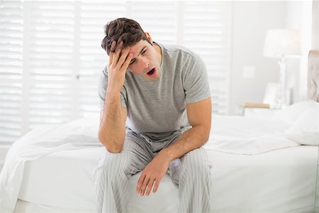 simsearch:640-06051744,k - Sleepy young man sitting and yawning in bed at home Photographie de stock - Aubaine LD & Abonnement, Code: 400-07177830