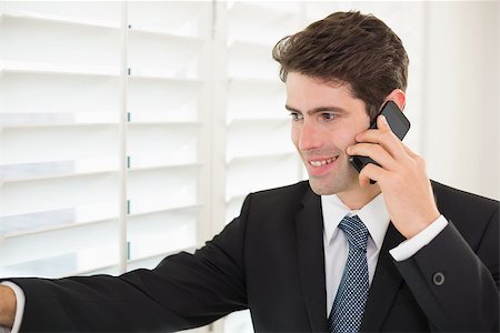 Smiling young businessman peeking through blinds while on call in office Stock Photo - Budget Royalty-Free & Subscription, Code: 400-07177859