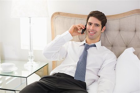 sophisticated home smile - Portrait of a smiling well dressed man using mobile phone in bed at home Stock Photo - Budget Royalty-Free & Subscription, Code: 400-07177907
