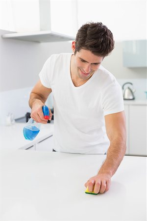 simsearch:400-07228658,k - Smiling young man cleaning kitchen counter in the house Stockbilder - Microstock & Abonnement, Bildnummer: 400-07178072