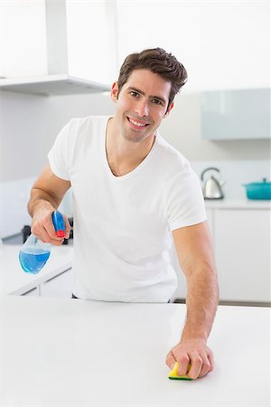 simsearch:400-07228658,k - Portrait of a smiling young man cleaning kitchen counter in the house Stockbilder - Microstock & Abonnement, Bildnummer: 400-07178073