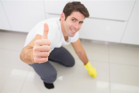 simsearch:400-04214184,k - Portrait of a smiling young man cleaning the kitchen floor while gesturing thumbs up at house Stockbilder - Microstock & Abonnement, Bildnummer: 400-07178081