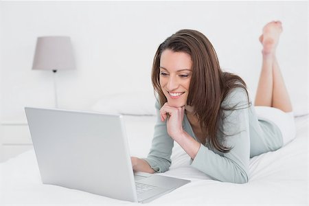 Relaxed casual smiling young woman using laptop in bed at home Stock Photo - Budget Royalty-Free & Subscription, Code: 400-07178619