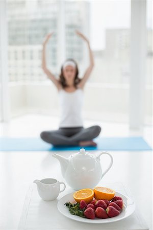 simsearch:400-07135317,k - Blurred toned young woman sitting in meditation posture with healthy food in foreground at fitness studio Photographie de stock - Aubaine LD & Abonnement, Code: 400-07178715