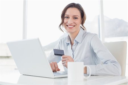 simsearch:400-07333971,k - Portrait of a smiling businesswoman doing online shopping through laptop and credit card in office Stock Photo - Budget Royalty-Free & Subscription, Code: 400-07178799
