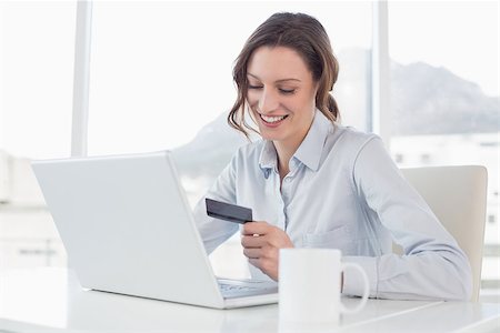 simsearch:400-07333971,k - Smiling businesswoman doing online shopping through laptop and credit card in office Stock Photo - Budget Royalty-Free & Subscription, Code: 400-07178800