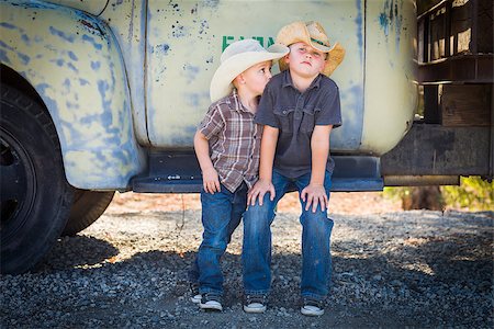 Two Young Boys Wearing Cowboy Hats Leaning Against an Antique Truck in a Rustic Country Setting. Foto de stock - Super Valor sin royalties y Suscripción, Código: 400-07179042