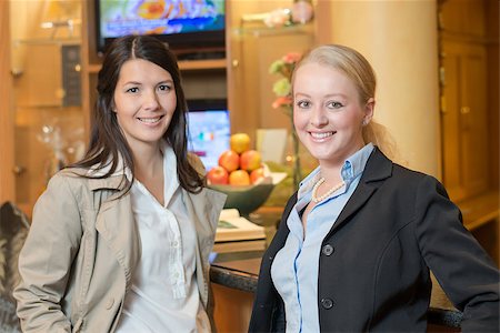 reception relaxed smile - Two beautiful stylish women friends standing together inside a luxury room interior looking at the camera with friendly smiles Stock Photo - Budget Royalty-Free & Subscription, Code: 400-07173059