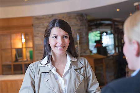 Smiling attractive young female guest in a hotel lobby talking to the receptionist as she checks in on her arrival Stock Photo - Budget Royalty-Free & Subscription, Code: 400-07173068