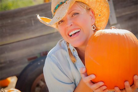 simsearch:400-07173780,k - Beautiful Blond Female Rancher Wearing Cowboy Hat Holds a Pumpkin in a Rustic Country Setting. Stockbilder - Microstock & Abonnement, Bildnummer: 400-07173768