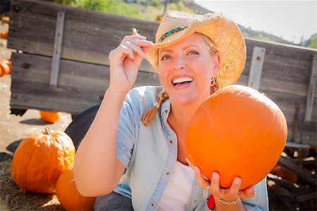 simsearch:400-07173780,k - Beautiful Blond Female Rancher Wearing Cowboy Hat Holds a Pumpkin in a Rustic Country Setting. Stockbilder - Microstock & Abonnement, Bildnummer: 400-07173769