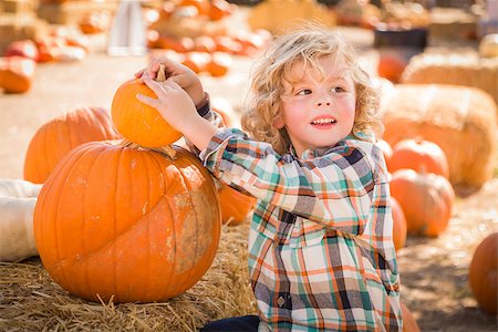 simsearch:400-07179959,k - Adorable Little Boy Sitting and Holding His Pumpkin in a Rustic Ranch Setting at the Pumpkin Patch. Stockbilder - Microstock & Abonnement, Bildnummer: 400-07173772